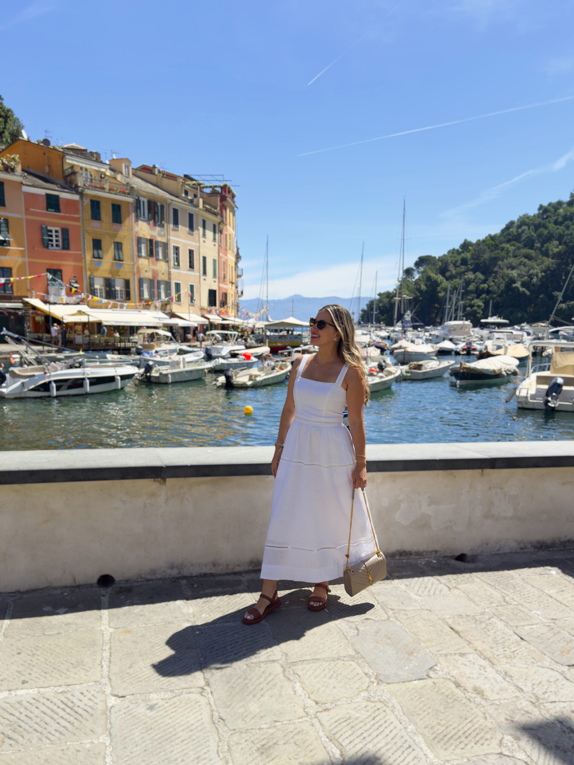 Travel blogger in a neutral linen outfit standing at Portofino Bay, showcasing what to wear in Portofino