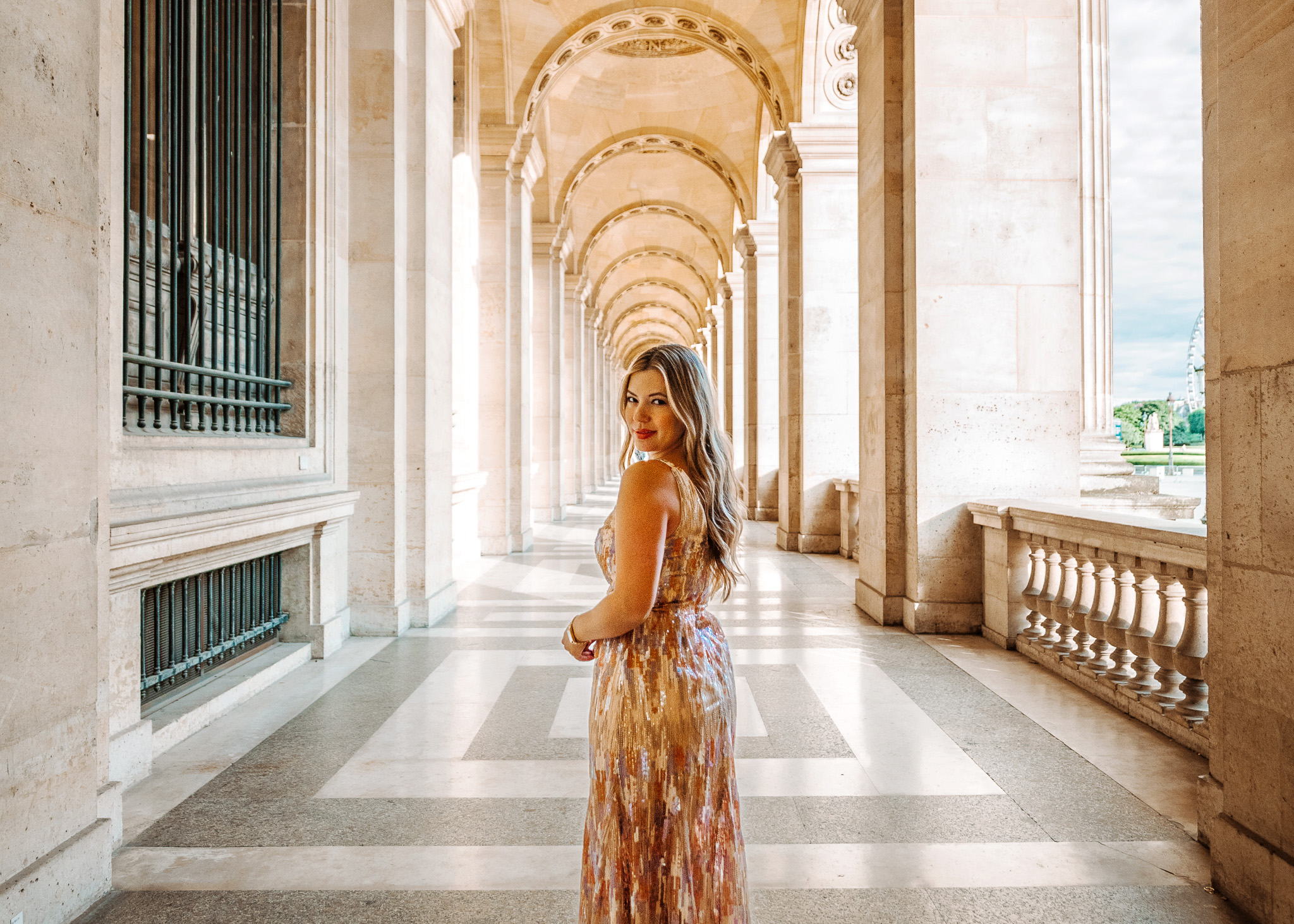 Woman in a chic dress posing at the Louvre in Paris during early morning, part of a fall 2025 Europe outfit guide.
