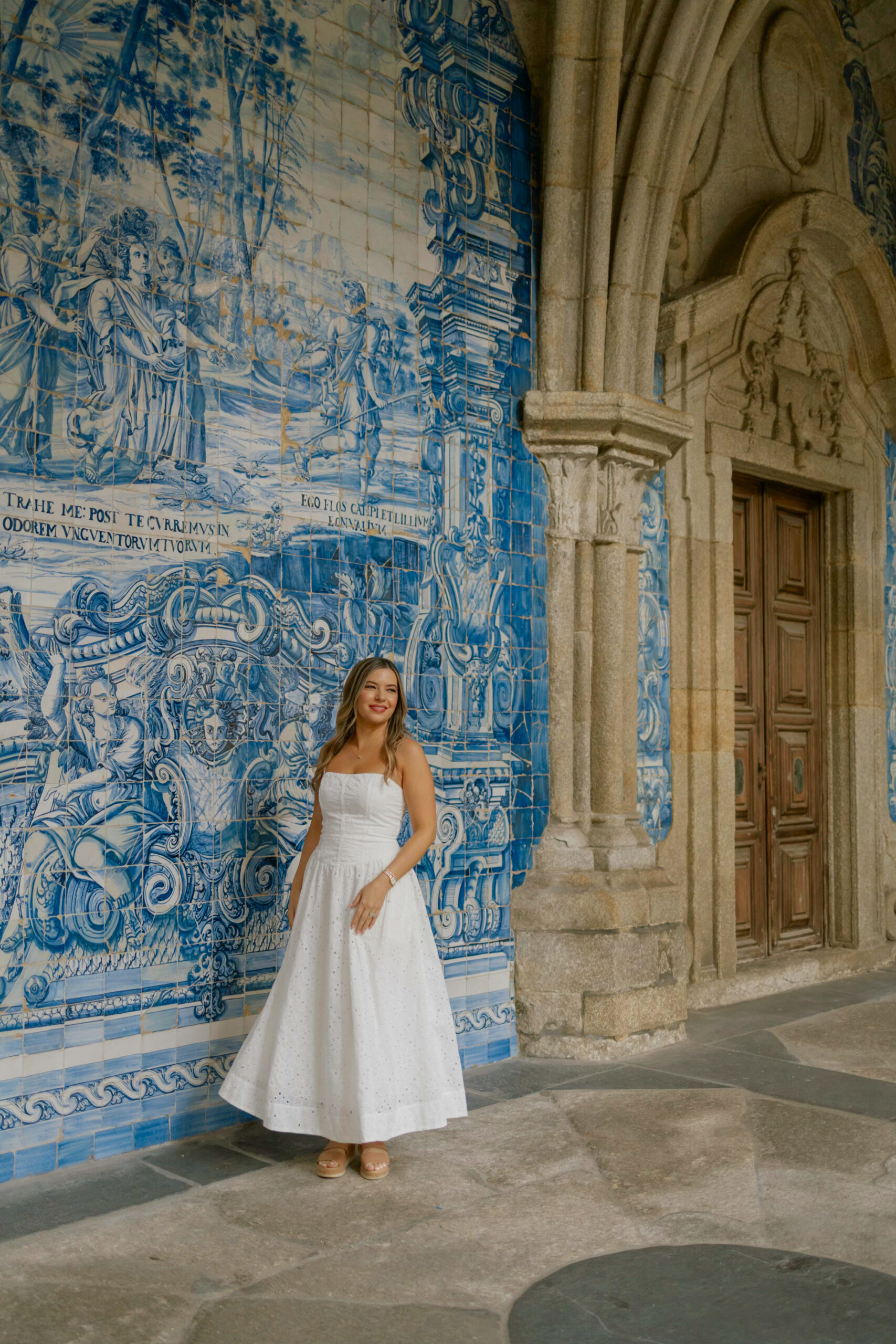 Woman standing in front of Porto Cathedral’s blue-tiled church façade wearing a neutral linen outfit, embodying effortless European style against the city’s iconic azulejo backdrop.