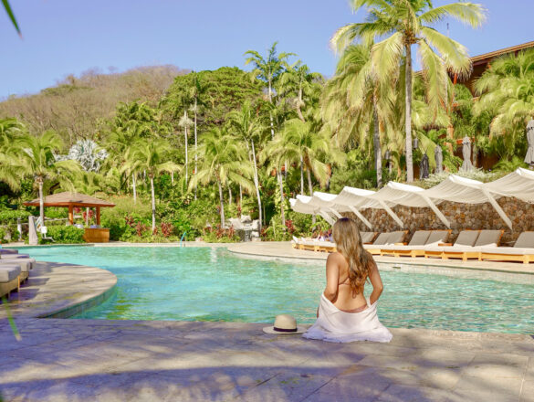 Woman relaxing at the Four Seasons Resort Peninsula Papagayo pool in Costa Rica with Pacific Ocean views.