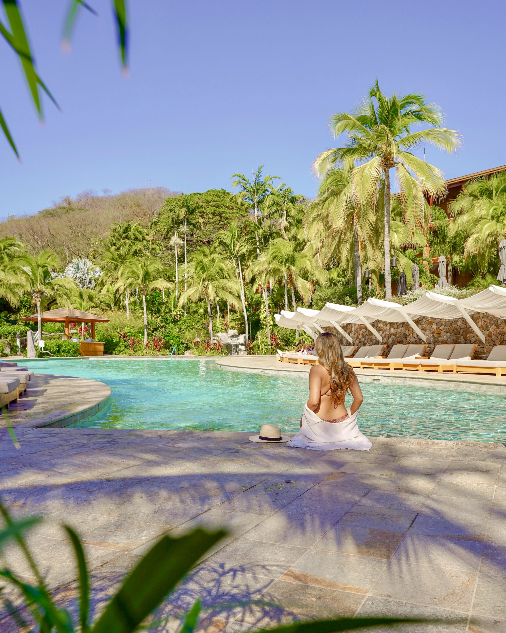 Woman relaxing at the Four Seasons Resort Peninsula Papagayo pool in Costa Rica with Pacific Ocean views.